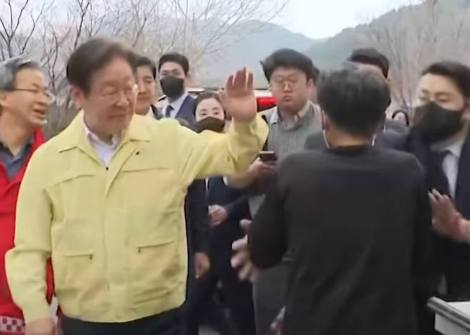 지난 27일 경북 영양군 이재민 대피소 인근에서 검은 옷을 입은 남성이 더불어민주당 이재명 대표를 향해 옷을 휘두르는 모습. MBN 보도화면 캡처
