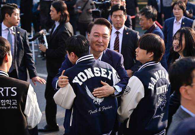 윤석열 전 대통령이 11일 오후 서울 용산구 한남동 관저 정문에서 퇴거하며 배웅 나온 학생들과 포옹하고 있다. /뉴스1