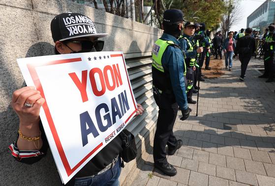 윤석열 전 대통령이 한남동 관저를 떠나 서초동 사저로 거처를 옮기는 것으로 알려진 11일 서울 서초구 사저 아크로비스타 인근에서 한 지지자가 손팻말을 들고 있다. 연합뉴스
