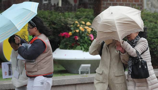 강풍을 동반한 눈비가 갑작스럽게 내린 13일 오후 서울 중구 덕수궁 인근에서 시민들이 발걸음을 재촉하고 있다. /박성원 기자