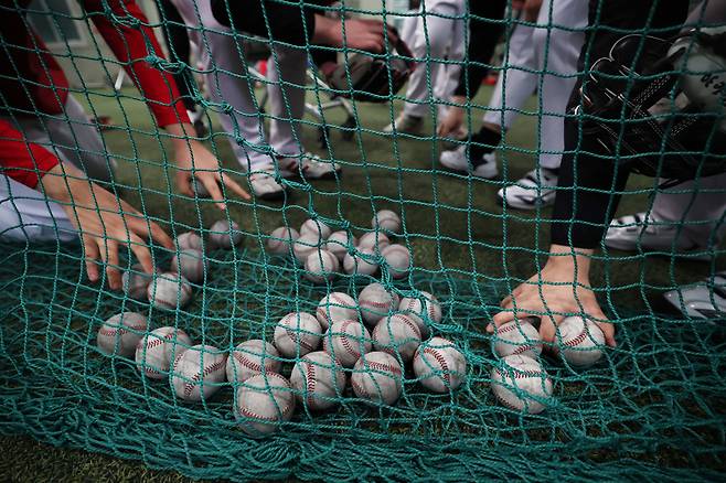공 던지기 훈련이 끝나고 네트 앞에는 공이 수북이 쌓였다. 다른 아이들도 모여 함께 공을 줍고 있다.