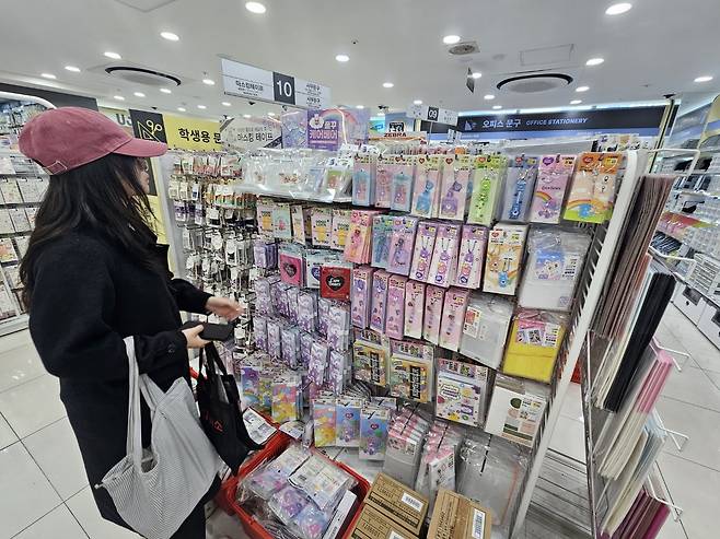 Nguyen Mai browses items, from plastic cases and albums to photos of her favorite idol, on Wednesday at a Daiso branch near Myeong-dong Station. (Choi Jae-hee/The Korea Herald)