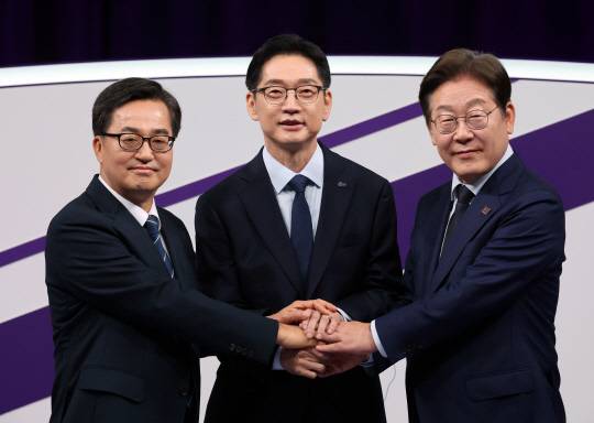 더불어민주당 대선 경선에 나선 이재명(오른쪽부터)·김경수·김동연 후보가 18일 서울 마포구 상암동 MBC에서 첫 TV토론회를 시작하기에 앞서 손을 잡고 기념촬영 하고 있다.<국회사진기자단·연합뉴스>