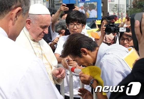 프란치스코 교황이 16일 서울 광화문 광장에서 열린 '윤지충 바오로와 동료 순교자 123위 시복식' 카 퍼레이드 도중 오픈카에서 내려 '세월호 특별법' 제정을 요구하며 34일째 단식중인 '유민 아빠' 김영오(47)씨를 위로하고 있다. (교황방한위원회 제공) 2014.8.16/뉴스1