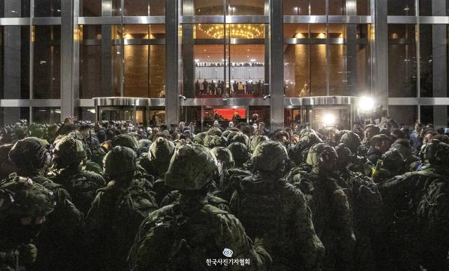 <61회 한국보도사진상 - 대상> 계엄군이 4일 새벽 국회 본관 정문 앞에서 국회 사무처 직원, 보좌진 등과 대치하고 있다. 계엄군은 정문이 막히자 사무실 유리창을 깨고 건물에 진입했지만, 의원들이 계엄 해제 요구안 표결을 위해 모인 본회의장에 들어가지는 않았다. 이날 국회에 투입된 병력은 약 280명으로 추정된다.사진 제공=한국사진기자협회(KPPA)