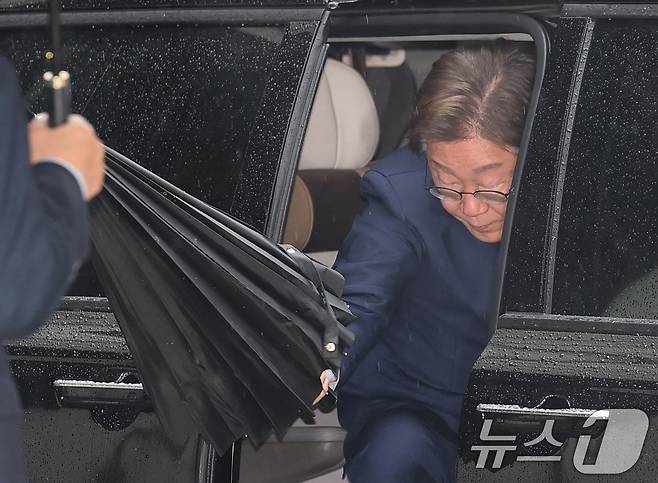 대권 도전에 나선 이재명 더불어민주당 전 대표가 22일 오전 서울 서초구 서울중앙지방법원에서 열린 '대장동 배임 및 성남FC 뇌물' 1심 속행 공판에 출석하기 위해 차량에서 내리며 우산을 펼치고 있다. 2025.4.22/뉴스1 ⓒ News1 오대일 기자
