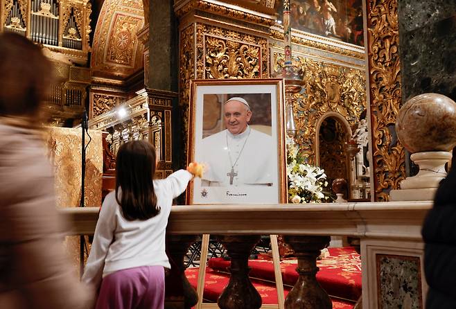 프란치스코 교황의 초상화를 어루만지는 어린아이. 로이터연합뉴스