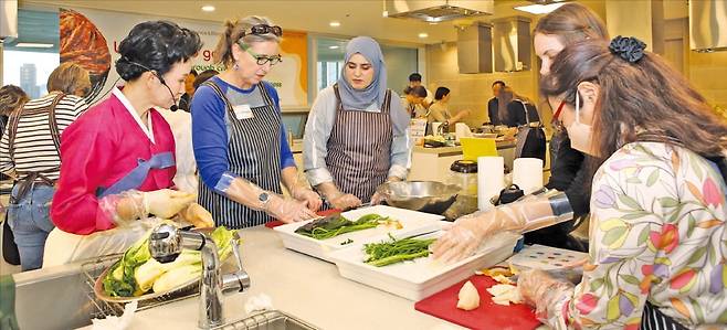지난달 27일 서울 송파구 가락몰 쿠킹스튜디오에서 열린 전통음식 체험 행사에서 외국인 참가자들이 이하연 김치 명인의 안내에 따라 직접 김치를 담그고 있다. /서울시농수산식품공사 제공