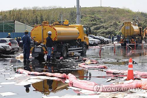 24일 오후 울산 울주군 온산읍 원산리의 한 도로에서 작업자들이 유출된 기름을 배관으로 빨아들이는 작업을 하고 있다. 연합뉴스