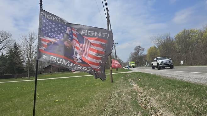 지난 25일 미국 미시건주 매컴카운티의 한 도로변. 트럼프 대통령을 지지하는 주민이 작년 7월 피격사건 사진을 담은 깃발을 꽂아놓고 있다. /매컴=이상은 특파원