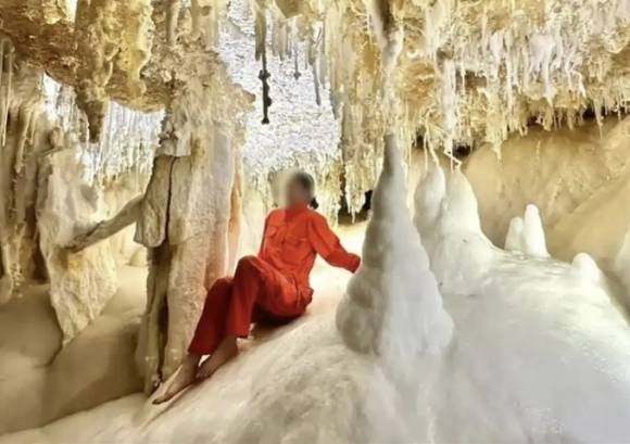 중국 구이저우성 다오전현에서 최근 발견돼 외부에 알려진 동굴 내부에서 투자유치를 위한 조사를 진행하던 한 여성이 맨발로 지층을 밟은 채 사진을 찍고 있다. 이 동굴은 4억 8000만년 전 형성된 지층으로 이뤄졌다. 자료 : 베이징완보