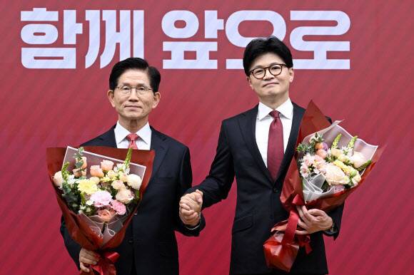 국민의힘 대선 최종 경선에 진출한 김문수(왼쪽)·한동훈 후보가 29일 서울 여의도 당사에서 3차 경선 진출자 발표 뒤 꽃다발을 들고서 기념사진을 찍고 있다. 공동취재사진