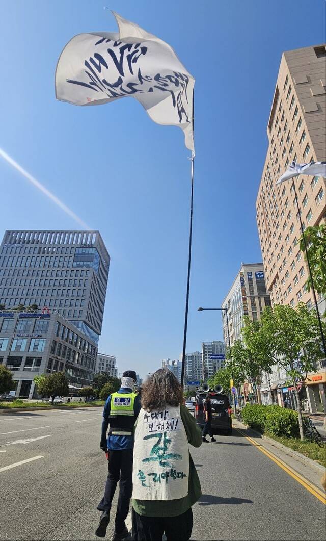 문성호 ‘보철거를 위한 금강·낙동강·영산강 시민행동’ 공동대표가 지난 29일 ‘생명의 편에 선 사람들’이라고 적힌 깃발을 들고 ‘세종보 천막농성 1년’을 맞아 진행한 거리행진을 이끌고 있다. 최예린 기자