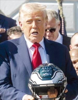 < 슈퍼볼 우승 헬멧에 적힌 MAGA > 도널드 트럼프 미국 대통령이 28일(현지시간) 백악관에서 열린 필라델피아 이글스의 2025년 슈퍼볼 우승 축하 행사에서 사인이 담긴 헬멧을 들어 보이고 있다. AFP연합뉴스