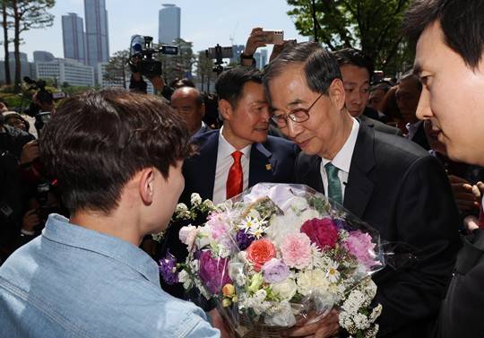한덕수 전 국무총리가 오늘(2일) 서울 여의도 국회 소통관에서 대선 출마 기자회견을 마친 뒤 건물을 나서던 중 한 청년으로부터 꽃을 받고 있다. (출처=뉴시스)