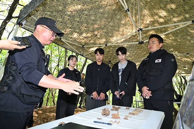 2일 발굴팀장(나군 최인건, 좌측)에게 현장에서 발굴된 유품에 대해 설명을 듣고 있는 최태성 역사 커뮤니케이터와 국방부·국가보훈부 2030 자문단. 국방부 제공