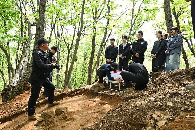 2일 발굴현장에서 실제 수습된 유해를 입관하고 태극기 관포하는 모습을 지켜보며 발굴팀장에게 관련 설명을 듣는 참석자들. 국방부 제공