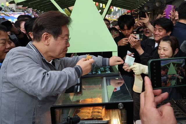 더불어민주당 이재명 대선 후보가 ‘골목골목 경청투어’ 사흘째인 3일 강원도 태백시 장성동 산나물 축제장에서 붕어빵을 사먹으며 지역화폐를 사용하고 있다. 연합뉴스
