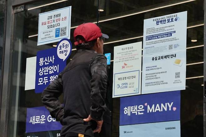 SK텔레콤 대리점 앞에서 한 소비자가 유심 재고 소진 및 유심보호서비스 관련 안내문을 살펴보고 있다. 연합뉴스