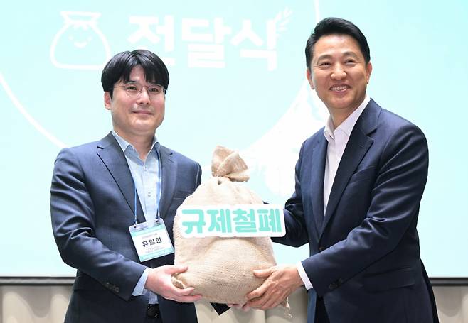 오세훈 서울시장이 7일 서울시청에서 열린 '규제철폐 100일 성과보고회'에서 시민 제안이 담긴 규제철폐 모래주머니를 전달받고 있다./사진=서울시