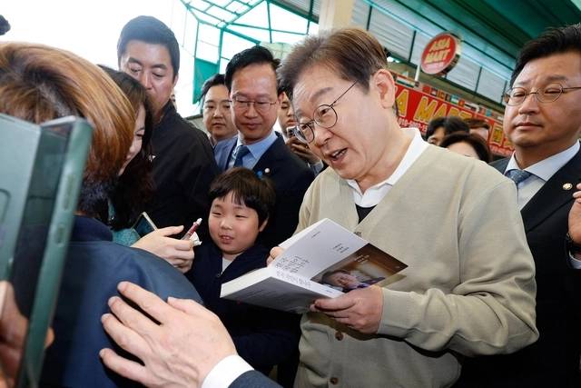 이재명 더불어민주당 대선 후보가 ‘골목골목 경청투어’ : 국토종주편‘에 나선 6일 충북 증평군 증평장뜰시장을 찾아 지지자가 건네준 책에 사인을 해주고 있다. 연합뉴스