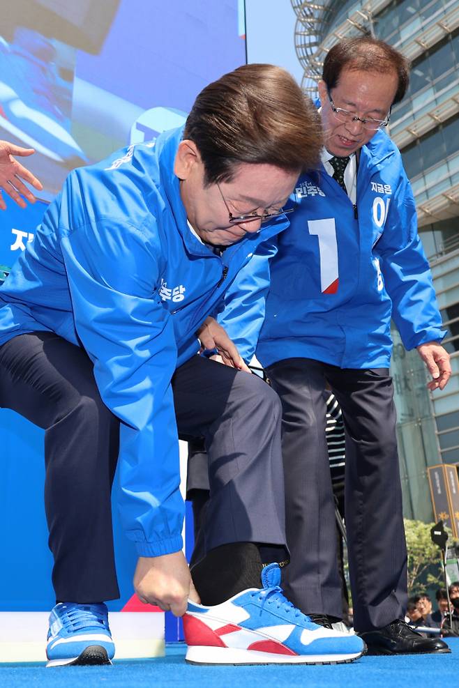민주당 고유 색인 파란색과 보수 진영을 상징하는 빨간색을 조합해 국민 통합의 의지를 시각적으로 표현하고자 한 것으로 분석된다. 사진은 이재명 더불어민주당 대통령 후보가제21대 대통령선거 공식 선거운동이 시작된 12일 오전 서울 종로구 청계광장에서 열린 중앙선거대책위원회 출정식에서 구두를 벗고 운동화를 신고 있는 모습. /사진=공동취재