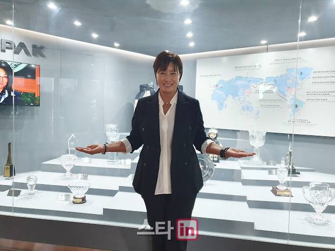 본인의 우승 트로피 앞에서 기념 촬영하는 박세리 감독.