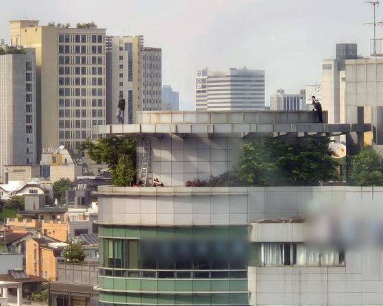 13일 서울 지하철 2호선 강남역 인근 빌딩 옥상에서 한 남성이 투신 소동을 벌여 경찰관과 구조대원들이 구조를 위해 접근하고 있다. 연합뉴스