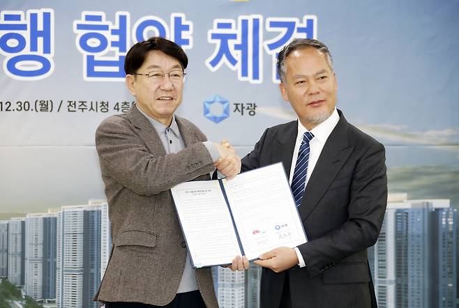 우범기(왼쪽) 전주시장과 전은수 ㈜자광 회장이 지난해 12월 30일 전주시청 4층 회의실에서 '옛 대한방직 부지 개발 사업 추진 공공 기여 및 사업 시행 협약'을 체결한 뒤 악수하고 있다. 사진 전주시