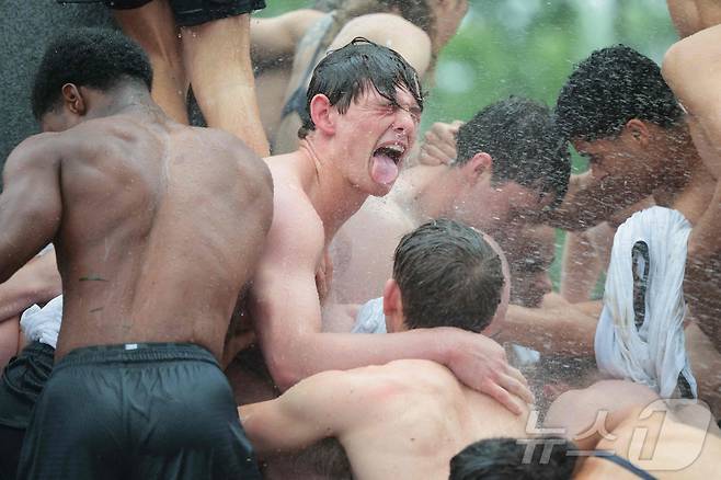 미국 해군사관학교에서 사관생도들이 14일(현지시간) 미국 메릴랜드 주 아나폴리스 미 해군 사관학교에서 '딕시 컵'을 떨어뜨리기 위해 인간 피라미드를 만들어 헌던 기념물 꼭대기에 오르고 있다. ⓒ AFP=뉴스1