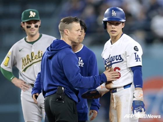 김혜성(오른쪽)이 지난 16일(한국 시각) 2루 도루를 성공시킨 뒤 왼손에 통증을 호소하자 의무진이 방문해 몸 상태를 확인하고 있다. /AFPBBNews=뉴스1