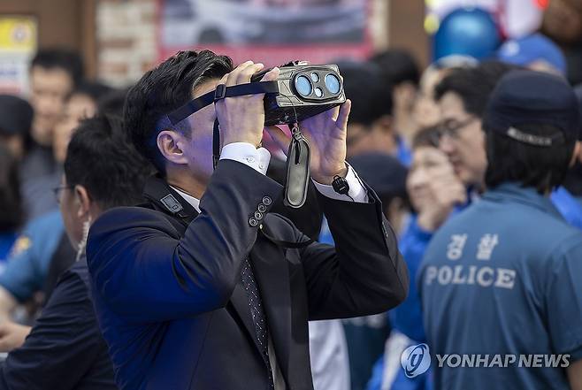 혹시 있을지 모를 위험에 대비해 (거제=연합뉴스) 황광모 기자 = 14일 경남 거제시에서 열린 더불어민주당 이재명 대선후보 유세에서 경호에 나선 경찰이 특수 쌍안경을 이용해 주변 건물의 움직임을 살피고 있다. 2025.5.14 hkmpooh@yna.co.kr