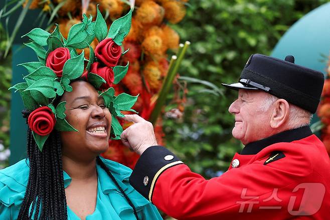 19일(현지시간) 영국 런던에서 열린 RHS 첼시 플라워쇼 프리뷰 행사에서 꽃무늬 머리 장식을 한 방문객이 대화를 나누고 있다. ⓒ 로이터=뉴스1