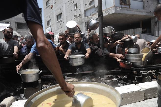 팔레스타인 사람들이 19일(현지시간) 가자지구 북부 자발리야 난민촌 식량 배급소에서 식량을 받고 있다. 신화연합뉴스