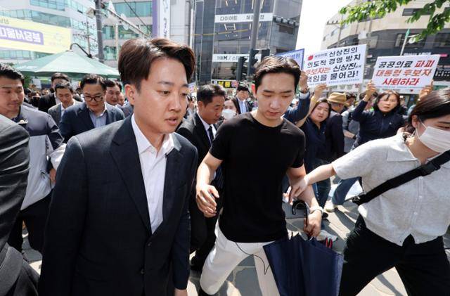 이준석 개혁신당 대선 후보가 21일 경기 성남시의료원에서 시민단체 회원들이 팻말을 들고 항의하는 목소리를 뒤로하며 본관으로 들어서고 있다. 성남=뉴시스