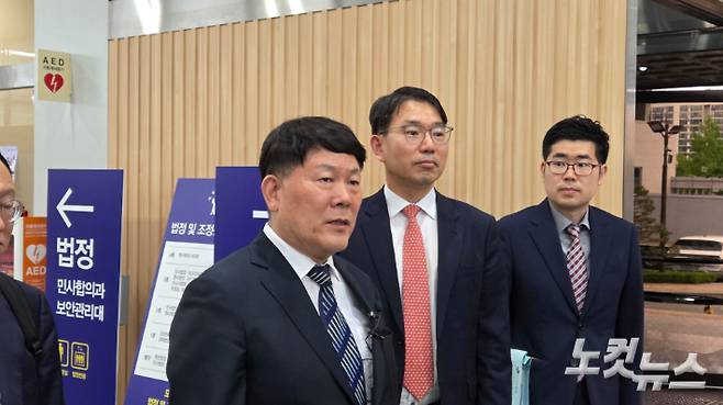 타이어뱅크 김정규 회장(왼쪽에서 두 번째)이 결심공판을 마친 뒤 기자들의 질문에 대답하는 모습. 김미성 기자