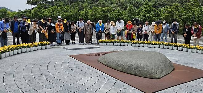 참배객들이 노무현 전 대통령 묘역에 둘러서서 묵념하고 있다.