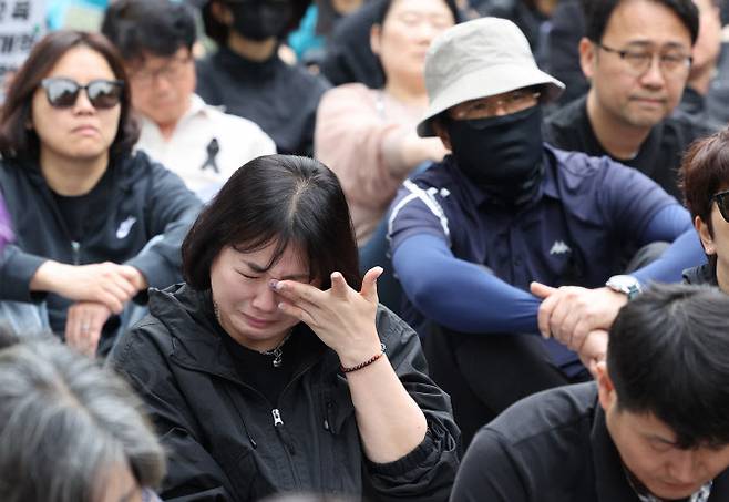 24일 서울 경복궁 영추문 앞에서 열린 전국교직원노동조합 창립 36주년 전국교사결의대회에서 한 참가자가 최근 제주도의 한 중학교에서 교사가 사망한 사건과 관련한 발언을 듣다 눈물을 흘리고 있다 (사진=연합뉴스)