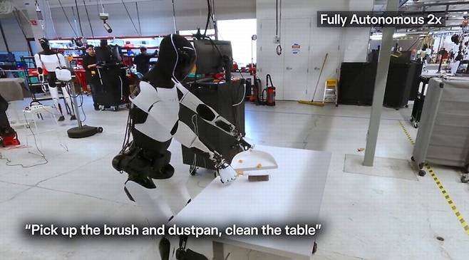 테슬라 옵티머스 로봇이 빗자루로 책상을 청소하는 모습. X 게시물 캡처