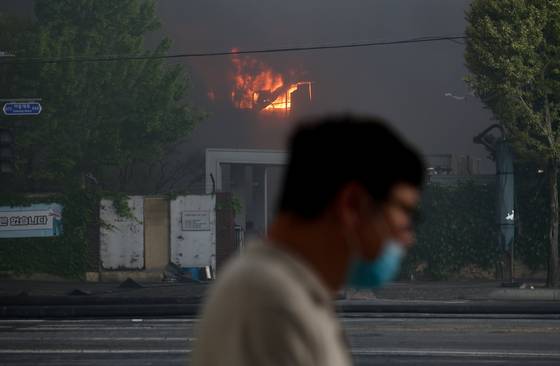 지난 17일 광주 광산구 금호타이어 광주공장에서 불이 나 검은 연기가 발생한 가운데 한 시민이 마스크를 쓰고 공장 인근을 지나가고 있다. 연합뉴스