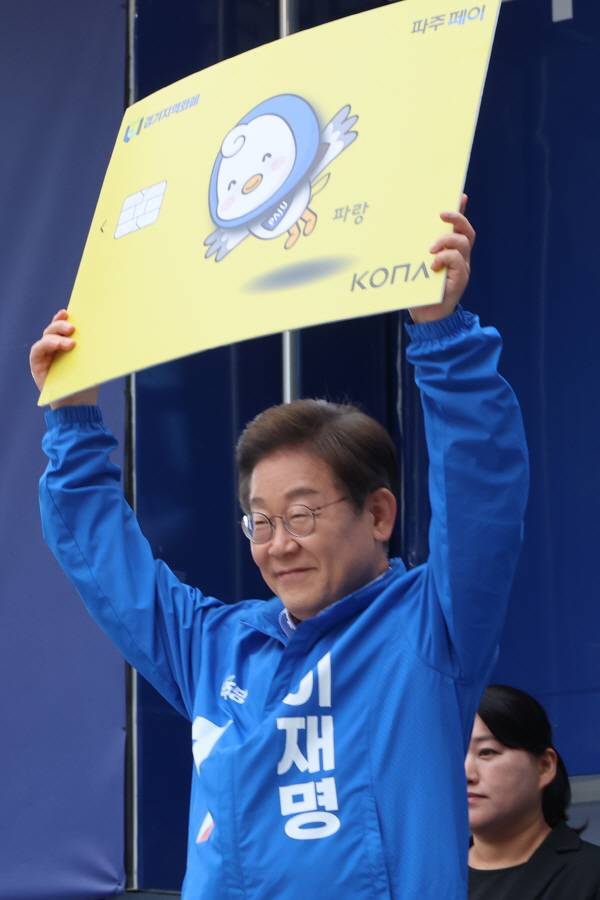 더불어민주당 이재명 대선 후보가 지난 20일 경기 파주시 금릉역 중앙광장에서 열린 유세에서 지역화폐 모형을 들어 보이고 있다. 연합뉴스