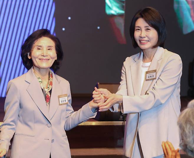 국민의힘 김문수 대선 후보의 부인 설난영 씨와 더불어민주당 이재명 대선 후보의 부인 김혜경 씨가 12일 서울 중구 신라호텔에서 열린 중앙신도회 창립 70주년 기념식에서 손을 맞잡고 있다. 연합뉴스