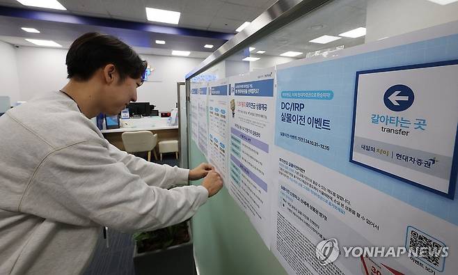 오늘부터 퇴직연금 갈아타기 '가능' (서울=연합뉴스) 이진욱 기자 = 기존 퇴직연금 상품을 다른 금융사로 옮길 수 있는 '퇴직연금 실물이전 서비스'가 31일부터 시작된다. 약 400조원 규모의 퇴직연금 시장에서 '머니무브'를 기대하는 은행·증권업계 경쟁이 치열해질 것으로 예상된다. 사진은 31일 서울 한 증권사 영업점에서 관계자가 관련 홍보물을 부착하는 모습. 2024.10.31 cityboy@yna.co.kr