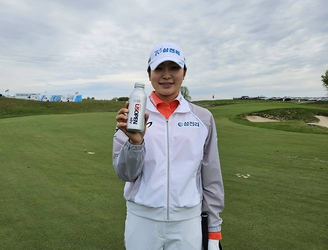 유현조가 연습 라운드를 하던 중 US여자오픈 로고가 새겨진 음료를 들고 환하게 웃고 있다. 넥스트크리에이티브