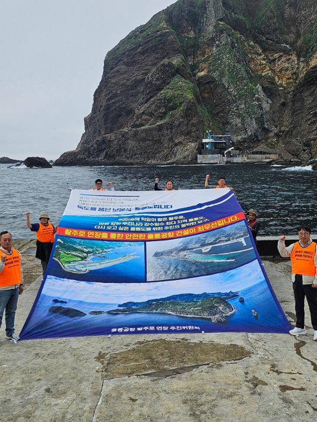 경북 울릉군 주민들이 17일 독도에서 울릉공항 조감도가 인쇄된 대형 현수막을 펼치고 활주로 연장을 촉구하는 집회를 하고 있다. 울릉공항 활주로 연장 추진위원회 제공