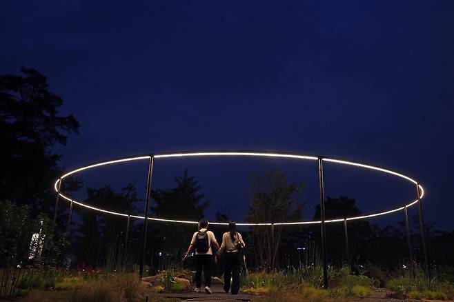 2025년 5월27일 저녁 서울 동작구 신대방동 보라매공원에서 열린 서울국제정원박람회에 시민들이 찾아와 작가정원을 둘러보고 있다. 이탈리아 조경가인 알레산드로 트리벨리의 ‘워터루츠!’(Waterrooots!). 작가는 “거대한 얼음덩어리가 녹아내리며 정원을 감싸는 원형 물 커튼이 되고, 흘러내린 물은 정원의 식생을 성장시킨다. 이 과정을 통해 기후변화를 가속하는 인간의 활동과 그럼에도 이뤄지는 자연의 회복력을 선보인다”고 설명한다.