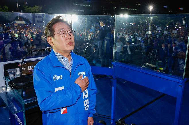더불어민주당 이재명 대선 후보가 선거를 하루 앞둔 2일 서울 여의도공원 마지막 유세에서 연설을 마친 뒤 애국가를 부르며 국기에 경례하고 있다. 연합뉴스
