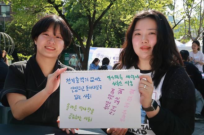 황다경(왼쪽)씨와 이유지씨가 지난달 25일 서울 중구 덕수궁 돌담길에서 21대 대통령 선거 이후 만나고 싶은 세계를 적어 보이고 있다. 김혜윤 기자 unique@hani.co.kr