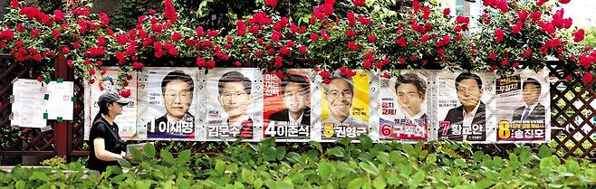 누가 꽃길 걸을까 - 한 시민이 6·3 대선을 하루 앞둔 2일 서울 용산구 한 아파트 화단에 걸린 대선 후보 벽보 앞을 지나가고 있다. 제21대 대통령 선거 투표는 3일 오전 6시부터 오후 8시까지 실시된다. /장경식 기자