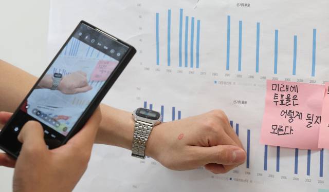 ▲제21대 대통령 선거일인 3일 대구 중구 동덕초등학교 1층 드라마실에 마련된 삼덕동 제2투표소에서 투표를 마친 유권자들이 투표소 밖 게시판에 붙어있는 초등학생들의 투표율 분석 게시물 앞에서 '투표 인증샷'을 남기고 있다. ⓒ연합뉴스